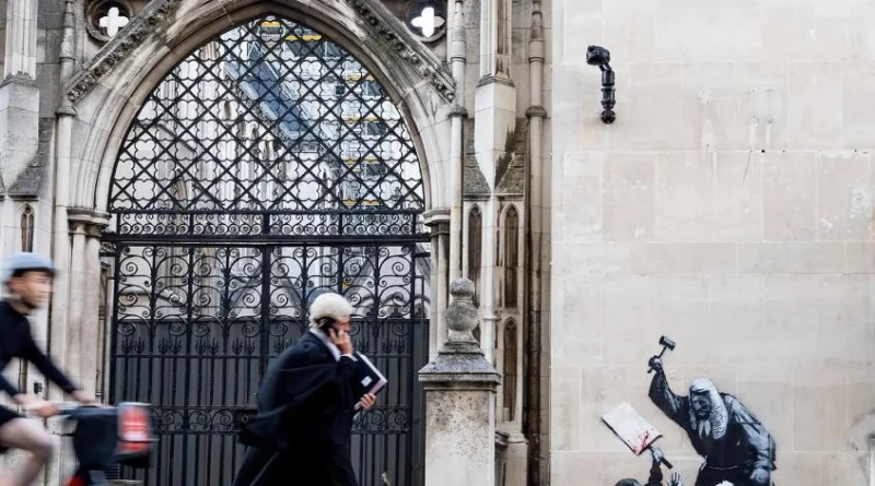 Banksy’s mural with the Royal Courts of Justice visible in the background, London, 2026. The setting is integral to the work, placing Banksy’s intervention in direct dialogue with the physical and symbolic architecture of British justice. Photo: ARTnews Japan.